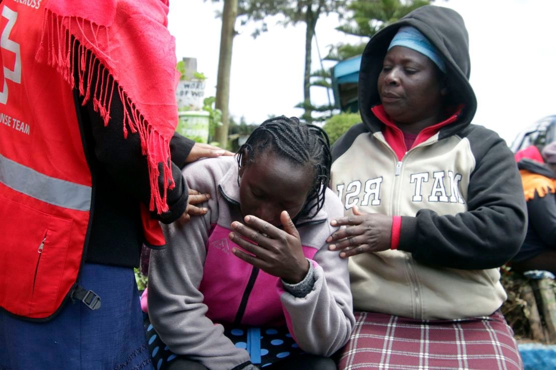 Kenya Red Cross personnel and relatives try to comfort a woman reacting near the burned-out dormitory.